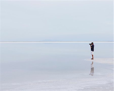 simsearch:6118-07122077,k - A Man Standing On The Edge Of The Flooded Bonneville Salt Flats, Taking A Photograph At Dusk. Stockbilder - Premium RF Lizenzfrei, Bildnummer: 6118-07122067