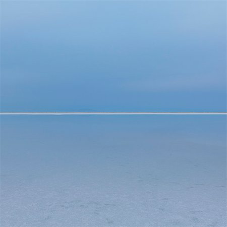 Shallow Water Over The Surface At The Bonneville Salt Flats Near Wendover, At Dusk. The Land Meeting The Sky On The Horizon, And A White Line Of Salt Crystals. Stock Photo - Premium Royalty-Free, Code: 6118-07122070