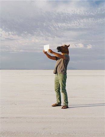 A Man Wearing A Horse Mask, Taking A Photograph With A Tablet Device, On Bonneville Salt Flats. Stock Photo - Premium Royalty-Free, Code: 6118-07122080