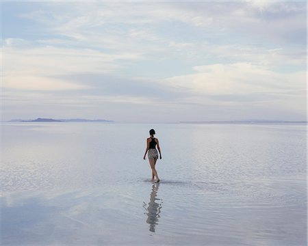 simsearch:6118-07122080,k - A Woman Standing On The Flooded Bonneville Salt Flats At Dusk. Reflections In The Shallow Water. Stock Photo - Premium Royalty-Free, Code: 6118-07122084