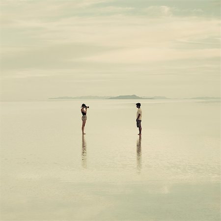 desastre natural - Man And Woman Standing On The Flooded Bonneville Salt Flats, Taking Photographs Of Each Other At Dusk. Foto de stock - Sin royalties Premium, Código: 6118-07122086