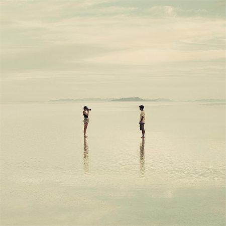 Man And Woman Standing On The Flooded Bonneville Salt Flats, Taking Photographs Of Each Other At Dusk. Stock Photo - Premium Royalty-Free, Code: 6118-07122086