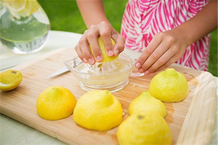 A Summer Family Gathering At A Farm. A Girl Slicing And Juicing Lemons To Make Lemonade. Photographie de stock - Premium Libres de Droits, Code: 6118-07122154