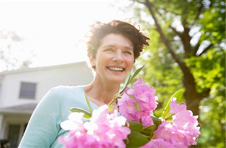 farmhouse - Family Party. A Woman Carrying A Large Bunch Of Rhododendron Flowers, Smiling Broadly. Stock Photo - Premium Royalty-Free, Code: 6118-07122195