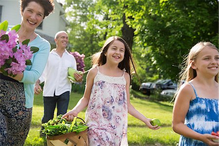 simsearch:6118-09183415,k - Family Party. Parents And Children Walking Across The Lawn Carrying Flowers, Fresh Picked Vegetables And Fruits. Preparing For A Party. Stockbilder - Premium RF Lizenzfrei, Bildnummer: 6118-07122199