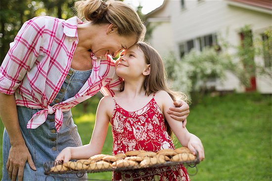 Baking Homemade Cookies. A Young Girl Holding A Tray Of Fresh Baked Cookies, And An Adult Woman Leaning Down To Praise Her. Photographie de stock - Premium Libres de Droits, Le code de l’image : 6118-07122245