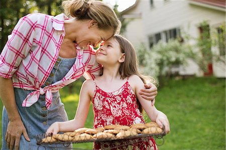 simsearch:6118-07122241,k - Baking Homemade Cookies. A Young Girl Holding A Tray Of Fresh Baked Cookies, And An Adult Woman Leaning Down To Praise Her. Stock Photo - Premium Royalty-Free, Code: 6118-07122245