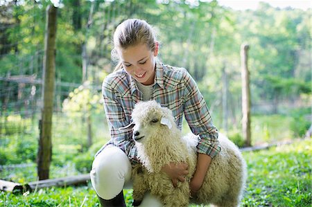 A Teenager Kneeling And Putting Her Arms Around A Very Curly Haired Angora Goat. Stock Photo - Premium Royalty-Free, Code: 6118-07122248