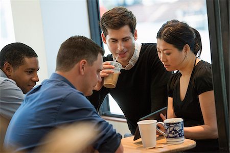 simsearch:649-05657883,k - A Group Of People Sitting Around A Table In A Coffee Shop. Looking At The Screen Of A Digital Tablet. Three Men And A Woman. Foto de stock - Sin royalties Premium, Código: 6118-07122299