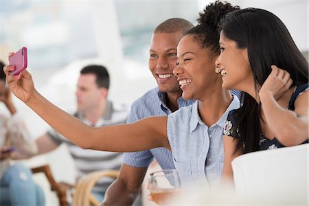 phone african american adults - Office Event. A Woman Taking A Selfie Of The Group With A Smart Phone. Stock Photo - Premium Royalty-Free, Code: 6118-07122342