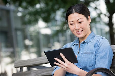 Summer. A Woman Sitting On A Bench Using A Digital Tablet. Foto de stock - Sin royalties Premium, Código: 6118-07122303