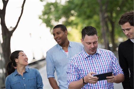 simsearch:6118-07122298,k - Summer In The City. Four People In A Group. One Using His Digital Tablet. Photographie de stock - Premium Libres de Droits, Code: 6118-07122307