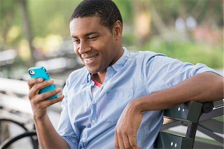 Summer In The City. A Man Sitting On A Bench Using A Smart Phone. Stock Photo - Premium Royalty-Free, Code: 6118-07122311