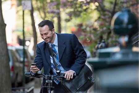 sustainable resource - A Man In A Business Suit, Outdoors In A Park. Sitting On A Bicycle. Stock Photo - Premium Royalty-Free, Code: 6118-07122474