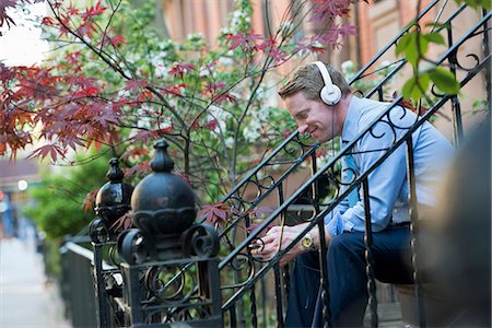 A Man In A Blue Shirt Wearing Headphones And Listening To A Music Player. Photographie de stock - Premium Libres de Droits, Code: 6118-07122483