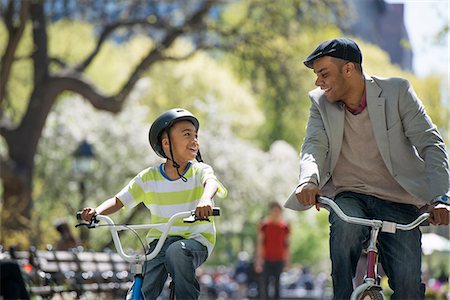 simsearch:6118-07122488,k - Bicycling And Having Fun. A Father And Son Side By Side. Photographie de stock - Premium Libres de Droits, Code: 6118-07122489