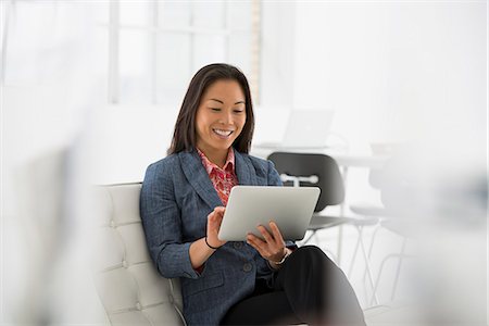 simsearch:6118-07122596,k - Business. A Woman Sitting Down Using A Digital Tablet. Fotografie stock - Premium Royalty-Free, Codice: 6118-07122546