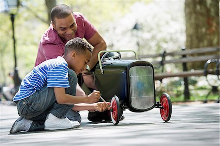 A Boy Repairing An Old Fashioned Toy Peddle Car. Stock Photo - Premium Royalty-Free, Code: 6118-07122501