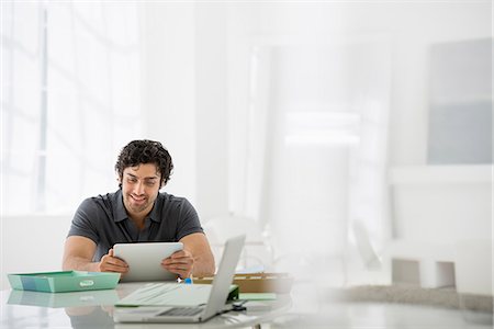 Business. A Light Airy Office Environment. A Man Sitting Holding A Digital Tablet. Photographie de stock - Premium Libres de Droits, Code: 6118-07122613