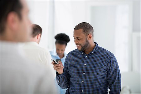 facial expression - Office Interior. A Group Of People, One Man Using A Smart Phone. Foto de stock - Sin royalties Premium, Código: 6118-07122638