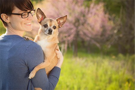 dog and outdoors - A Young Woman In A Grassy Field In Spring. Holding A Small Chihuahua Dog In Her Arms. A Pet. Stock Photo - Premium Royalty-Free, Code: 6118-07122747