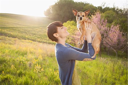 sentido - A Young Woman In A Grassy Field In Spring. Holding A Small Chihuahua Dog In Her Arms. A Pet. Foto de stock - Sin royalties Premium, Código: 6118-07122750