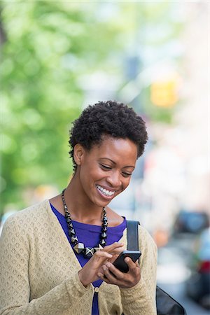 City. A Woman In A Purple Dress Checking Her Smart Phone. Stock Photo - Premium Royalty-Free, Code: 6118-07122786
