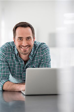 Office Interior. A Man Seated At A Table, Using A Laptop Computer. Stock Photo - Premium Royalty-Free, Code: 6118-07122724