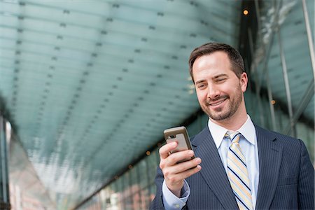 person looking at smart phone - City. A Man In A Business Suit Checking His Messages On His Smart Phone. Stock Photo - Premium Royalty-Free, Code: 6118-07122842