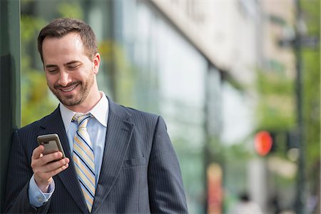 people looking down smart phones - City. A Man In A Business Suit Checking His Messages On His Smart Phone. Stock Photo - Premium Royalty-Free, Code: 6118-07122829