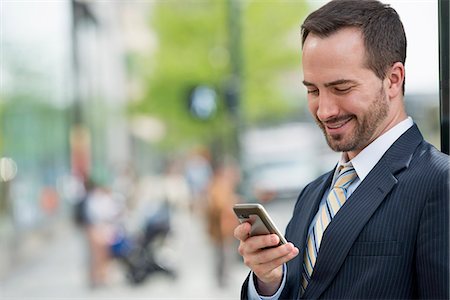 smart phone and texting and business and city - City. A Man In A Business Suit Checking His Messages On His Smart Phone. Stock Photo - Premium Royalty-Free, Code: 6118-07122830