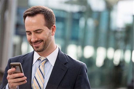 City. A Man In A Business Suit Checking His Messages On His Smart Phone. Stock Photo - Premium Royalty-Free, Code: 6118-07122834