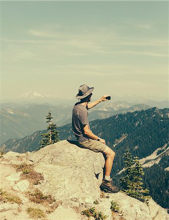 draufsicht - A hiker on a mountain summit, holding a smart phone, at the top of Surprise Mountain, in the Alpine Lakes Wilderness, in Mount Baker-Snoqualmie National Forest. Stockbilder - Premium RF Lizenzfrei, Bildnummer: 6118-07202945