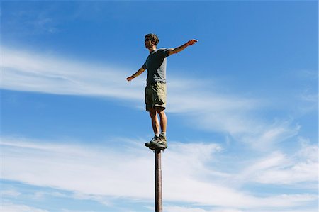 people risk - Man standing and balancing on a metal post, looking towards expansive sky, on Surprise Mountain, Alpine Lakes Wilderness, Mt. Baker-Snoqualmie National forest. Stock Photo - Premium Royalty-Free, Code: 6118-07202948