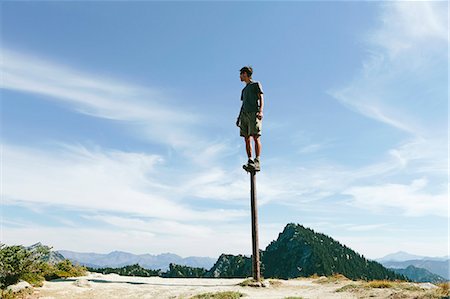 A man standing and balancing on a metal post, looking towards expansive sky, on Surprise Mountain, Alpine Lakes Wilderness, Mt. Baker-Snoqualmie national forest. Stockbilder - Premium RF Lizenzfrei, Bildnummer: 6118-07202949