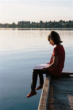 simsearch:6118-07351271,k - A young girl sitting on a dock, reading a book. Foto de stock - Sin royalties Premium, Código: 6118-07202934