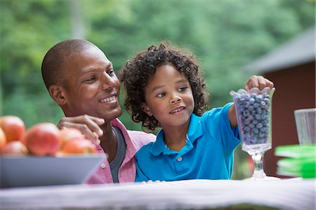 simsearch:6111-06837472,k - A picnic on the farm. Fresh organic fruit on the table. A father and son sitting together. Foto de stock - Sin royalties Premium, Código: 6118-07203061