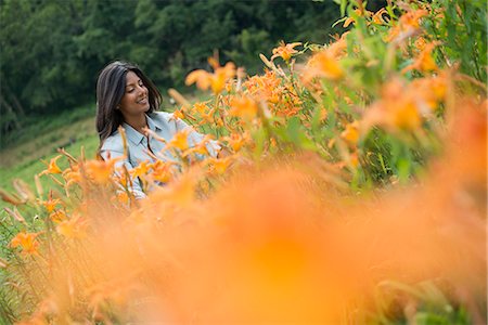 field of orange flowers - A woman standing among flowering plants on a farm. Stock Photo - Premium Royalty-Free, Code: 6118-07203021