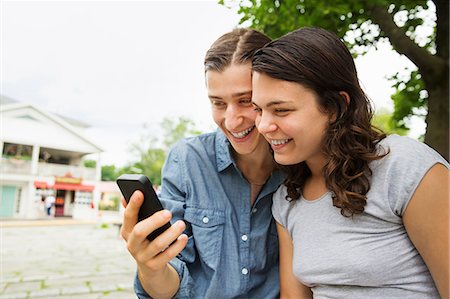 simsearch:6118-07203336,k - A young couple side by side, flirting and taking photographs. Photographie de stock - Premium Libres de Droits, Code: 6118-07203273