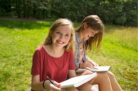 Two young girls sitting outside on the grass, with sketch pads and pencils. Foto de stock - Sin royalties Premium, Código: 6118-07203289