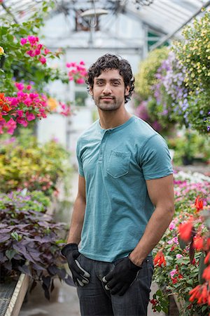 simsearch:6118-07203701,k - A young man working in a greenhouse full of flowering plants. Stock Photo - Premium Royalty-Free, Code: 6118-07203365