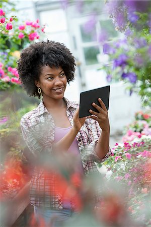 simsearch:6118-07354167,k - A woman in a plant nursery surrounded by flowering plants and green foliage. Foto de stock - Sin royalties Premium, Código: 6118-07203376