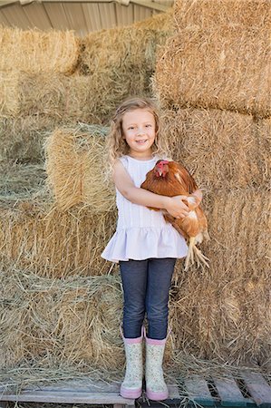 rain boots farm - A young girl standing in a hay barn holding a chicken in her arms. Stock Photo - Premium Royalty-Free, Code: 6118-07203317