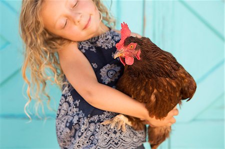 A young girl holding a chicken in her arms. Photographie de stock - Premium Libres de Droits, Code: 6118-07203320