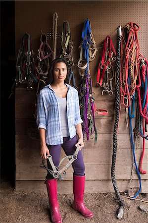 simsearch:6118-07203858,k - An organic farm in the Catskills. A person standing in a tack room in a stable. Stock Photo - Premium Royalty-Free, Code: 6118-07203330