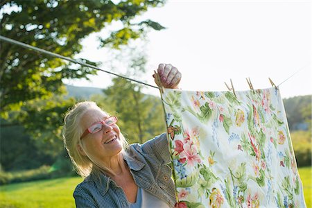 A woman hanging laundry on the washing line, in the fresh air. Stock Photo - Premium Royalty-Free, Code: 6118-07203469