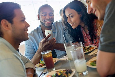 A group of men and women in a cafe, having drinks and enjoying each other's company. Stock Photo - Premium Royalty-Free, Code: 6118-07203489