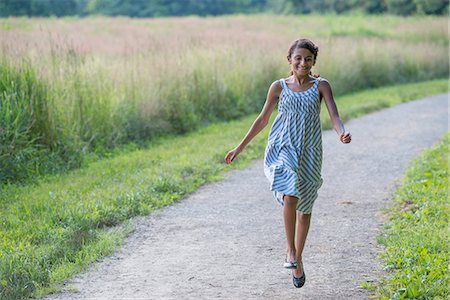 simsearch:6118-07203405,k - A young girl in a summer dress walking along a path. Foto de stock - Sin royalties Premium, Código: 6118-07203401