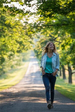 A woman walking down a tree lined path. Stockbilder - Premium RF Lizenzfrei, Bildnummer: 6118-07203404