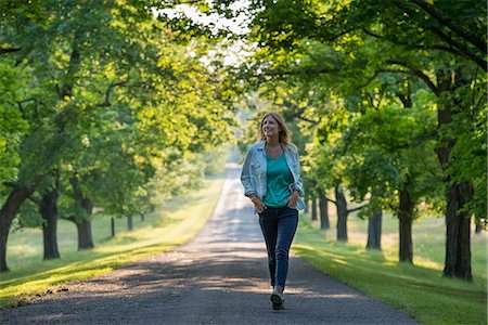 simsearch:6118-07203182,k - A woman walking down a tree lined path. Stock Photo - Premium Royalty-Free, Code: 6118-07203405